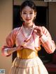 A woman in a pink and yellow hanbok is posing for a picture.