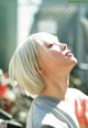 A woman with blonde hair is looking up at the sky.