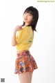 A young woman in a yellow shirt and colorful skirt.