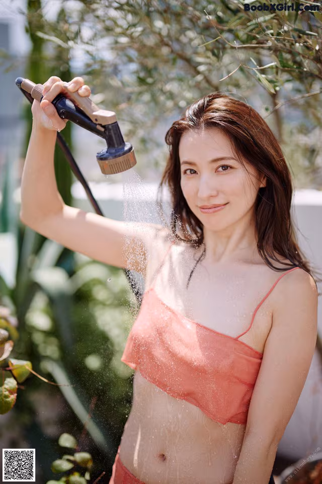 A woman in a pink bikini holding a shower head.