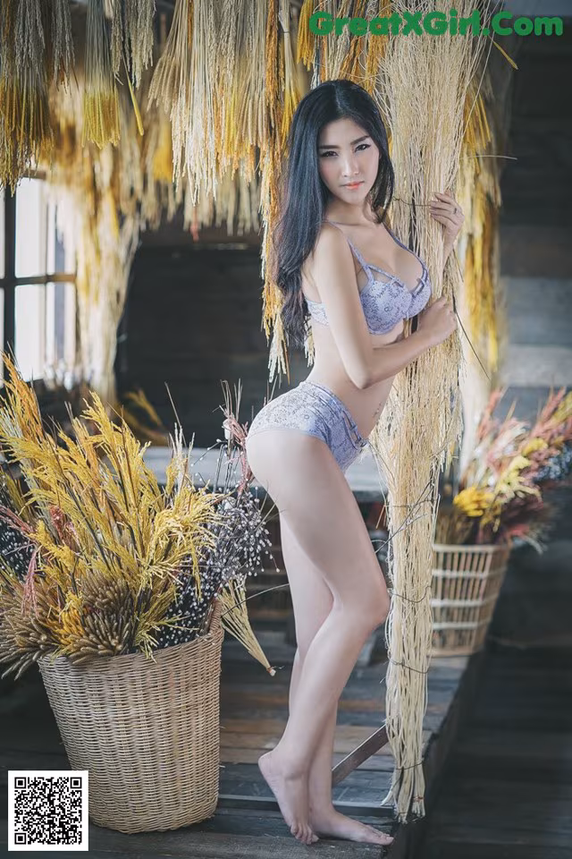 A woman in a bikini standing next to a basket of flowers.