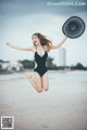 A woman in a black bathing suit jumping in the air.