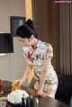 A woman in a cheongsam preparing food on a table.