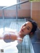 A woman laying in a bathtub with a towel on her head.