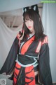 A woman in a black and red kimono with a cat ears headband.
