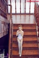 A woman in a white bodysuit sitting on a wooden staircase.