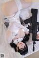 A woman laying on a bed holding a gun.