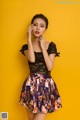 A woman in a black top and a floral skirt posing for a picture.