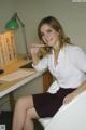 A woman sitting at a desk with a pencil in her mouth.