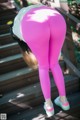 A woman in pink leggings is bending over on some steps.