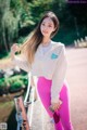 A woman in a white sweatshirt and pink leggings posing for a picture.