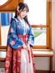 A woman in a blue and red hanbok standing by a window.