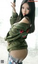 A woman in a green jacket and fishnet stockings posing for a picture.