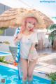 A woman in a white shirt and a straw hat standing in a pool.
