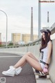 A woman sitting on a skateboard on the side of a road.